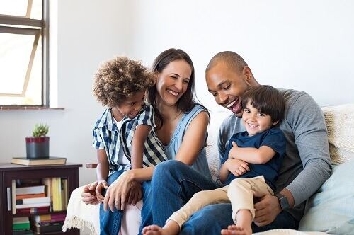 Family sitting on couch looking happy